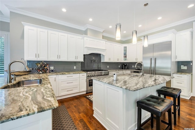 kitchen featuring sink, white cabinets, a kitchen island with sink, and high quality appliances