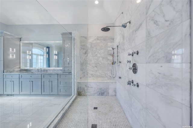 bathroom with tiled shower, vanity, and tile patterned flooring