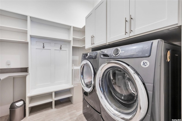 clothes washing area featuring washer and dryer, cabinets, and light hardwood / wood-style flooring