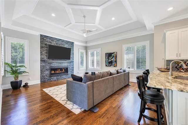 living room featuring dark wood-type flooring, ceiling fan, a stone fireplace, and sink