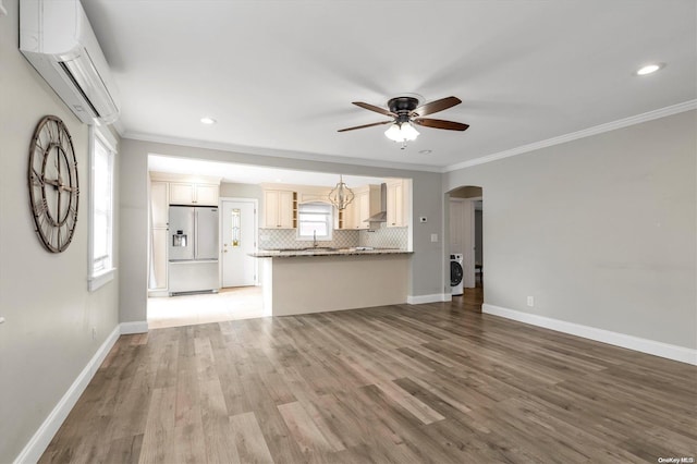 unfurnished living room with washer / clothes dryer, a wall mounted AC, and ornamental molding