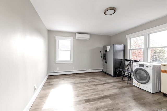 laundry area featuring baseboard heating, an AC wall unit, light wood-type flooring, and washer / dryer