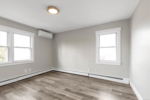 spare room featuring light wood-type flooring, baseboard heating, and a wall unit AC