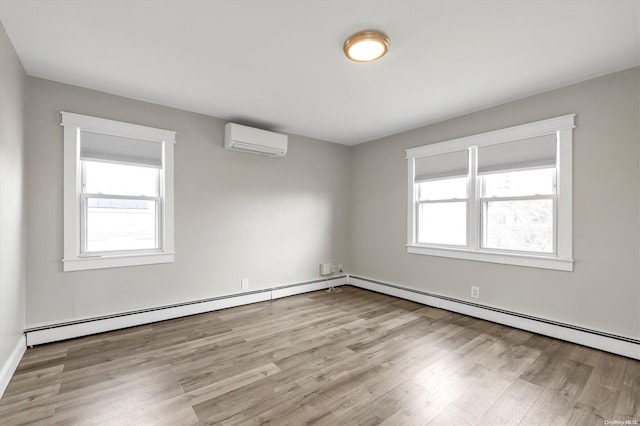 spare room with light wood-type flooring, an AC wall unit, and baseboard heating