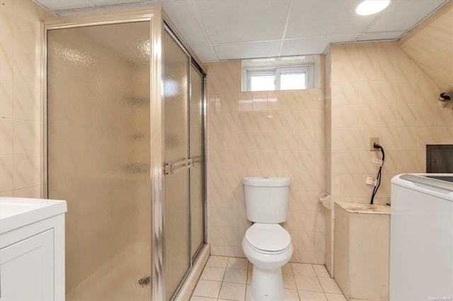 bathroom with tile patterned flooring, washer / dryer, tile walls, and walk in shower