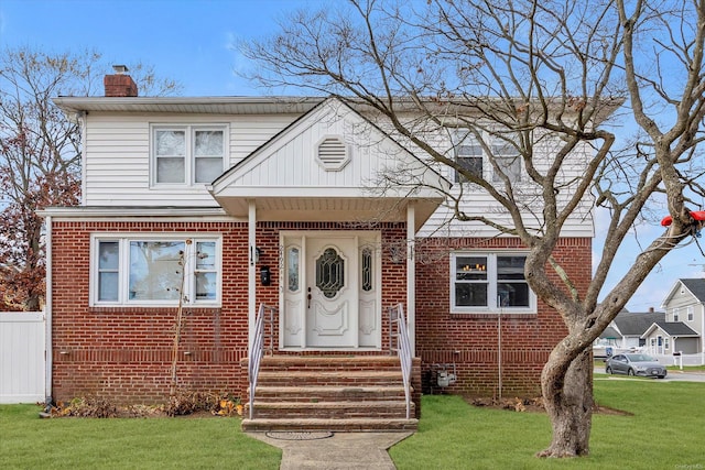 view of front of house featuring a chimney, a front yard, fence, and brick siding
