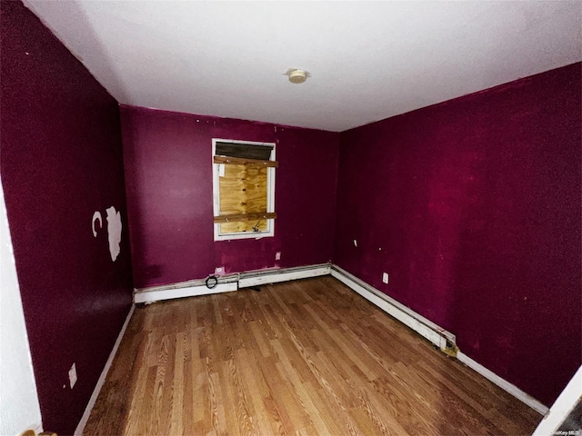 empty room with hardwood / wood-style floors and a baseboard heating unit