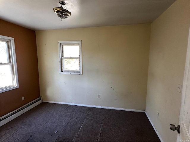 spare room featuring dark hardwood / wood-style floors, baseboard heating, and a wealth of natural light