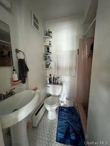 bathroom with toilet, a baseboard radiator, and a shower with shower curtain