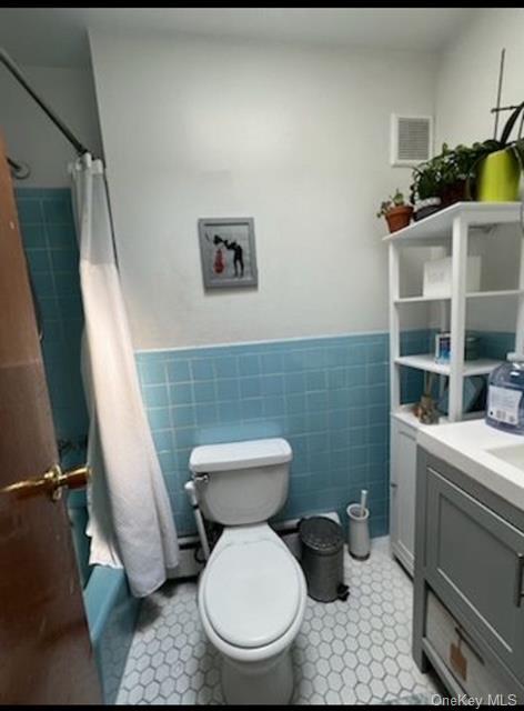 bathroom with vanity, tile walls, a shower with shower curtain, and toilet