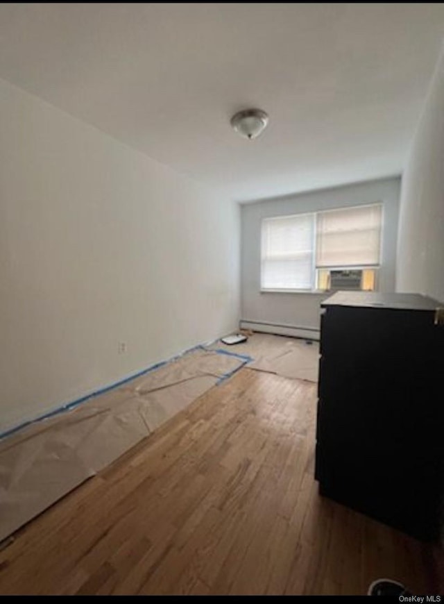 unfurnished room featuring a baseboard radiator and light wood-type flooring