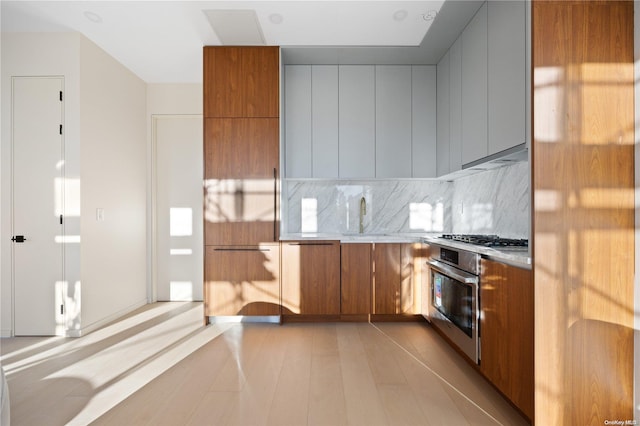 31-16 21st St Unit 3C, Astoria, NY 11106 - kitchen with stainless steel appliances, brown cabinets, backsplash, modern cabinets, and light countertops