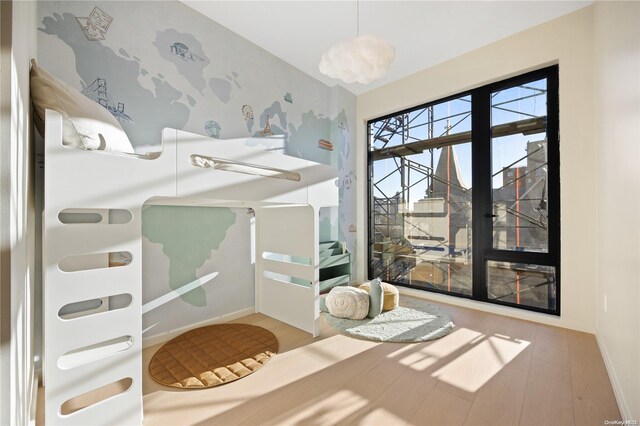 31-16 21st St Unit 3C, Astoria, NY 11106 - bedroom with wood finished floors, baseboards, and wallpapered walls