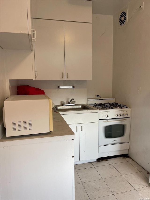 kitchen with white cabinetry, white gas stove, light tile patterned flooring, and sink