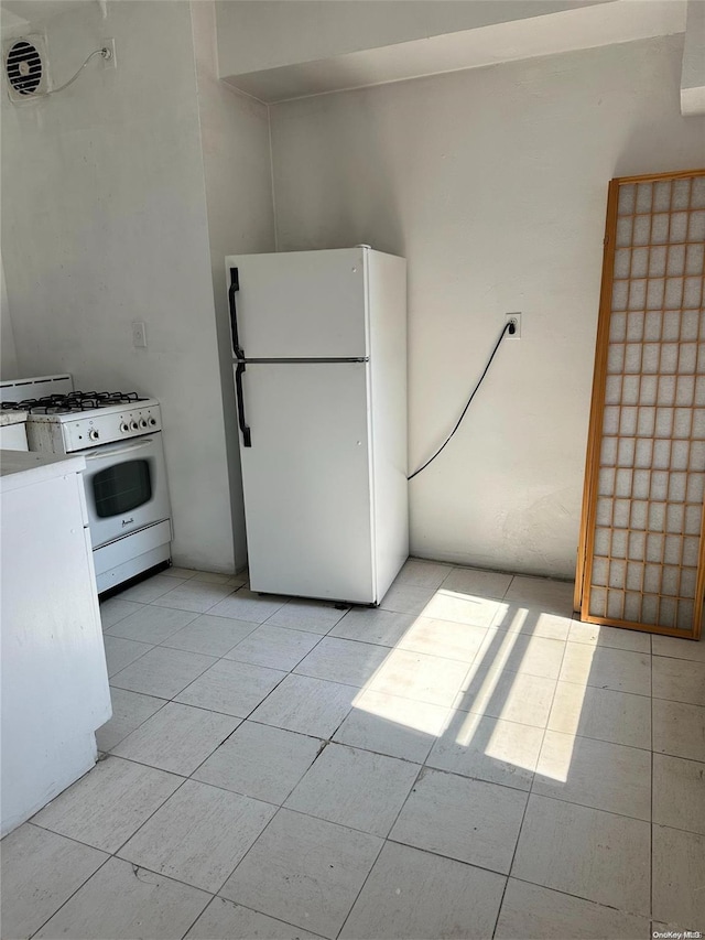 kitchen featuring light tile patterned flooring and white appliances