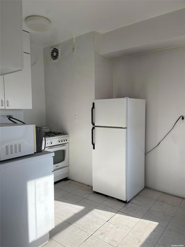 kitchen featuring light tile patterned flooring and white appliances