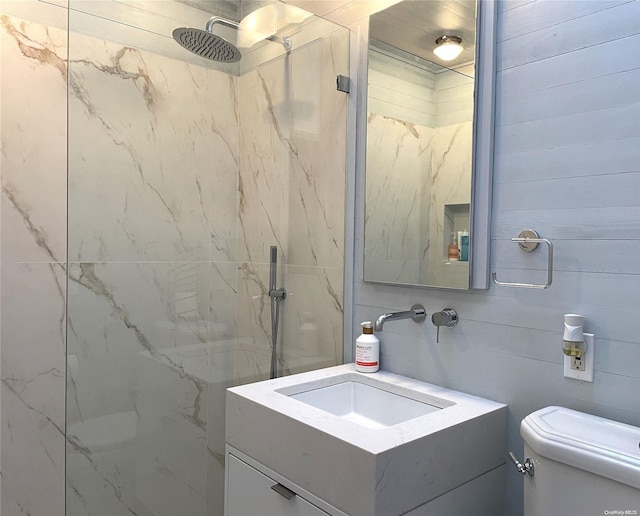 bathroom featuring a tile shower, vanity, and toilet