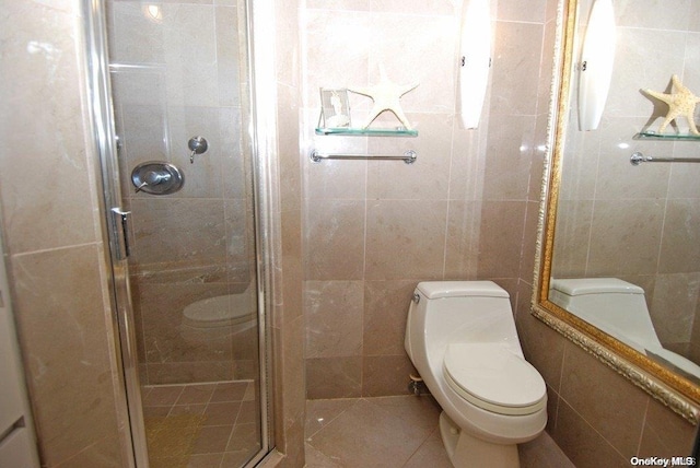 bathroom featuring tile patterned flooring, toilet, an enclosed shower, and tile walls