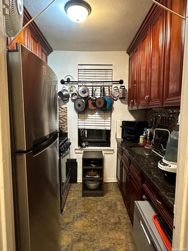 kitchen with stainless steel refrigerator, dark stone countertops, and sink