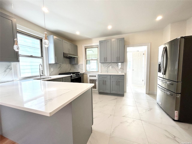 kitchen featuring kitchen peninsula, appliances with stainless steel finishes, a healthy amount of sunlight, and sink