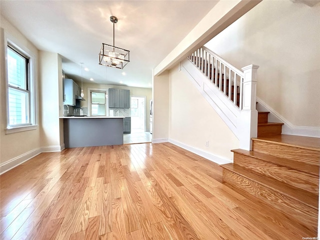 unfurnished living room with light hardwood / wood-style flooring and a notable chandelier