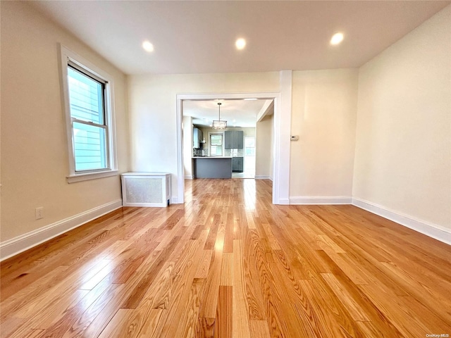 unfurnished room featuring radiator heating unit and light hardwood / wood-style floors