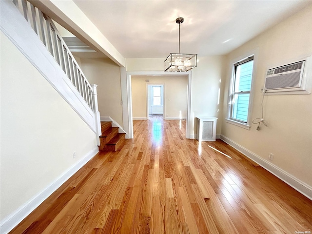 foyer entrance with a chandelier, light wood-type flooring, and an AC wall unit