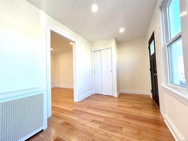 hall with radiator heating unit and light wood-type flooring