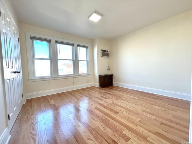 unfurnished room with light hardwood / wood-style floors and a wall unit AC