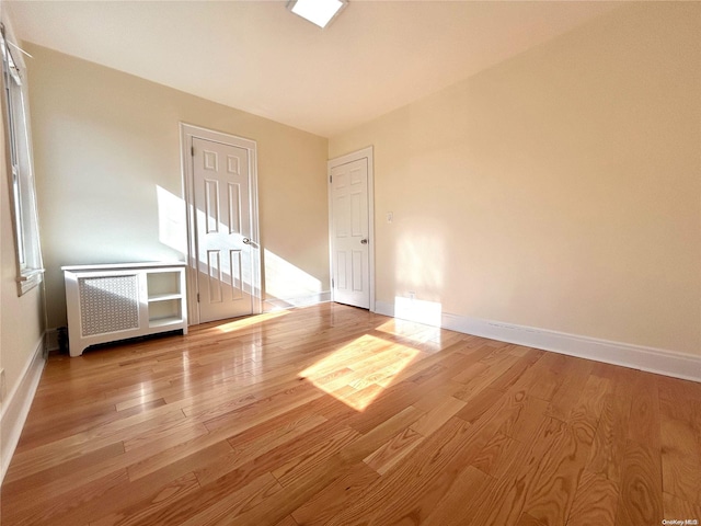 unfurnished room with radiator and light hardwood / wood-style flooring