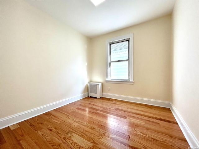 unfurnished room featuring radiator heating unit and light hardwood / wood-style flooring