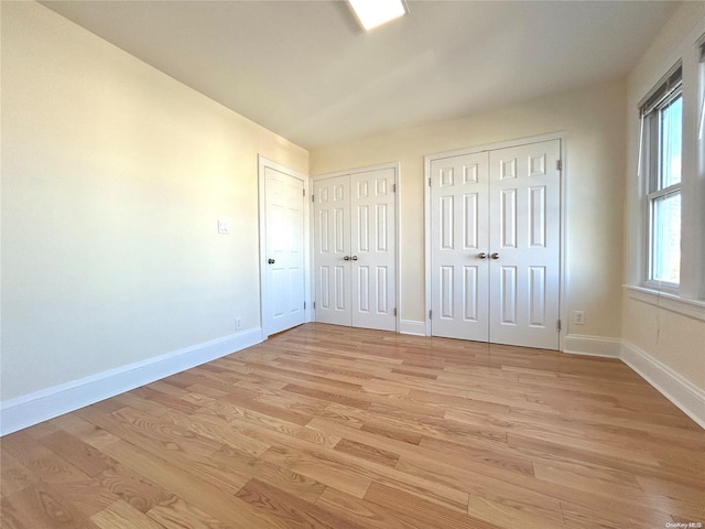 unfurnished bedroom with multiple closets and light hardwood / wood-style floors