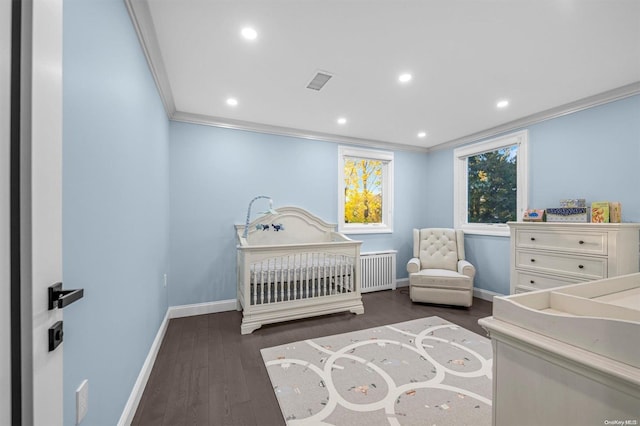 bedroom with radiator, crown molding, dark hardwood / wood-style flooring, and a nursery area