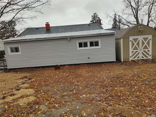 rear view of property featuring a storage unit