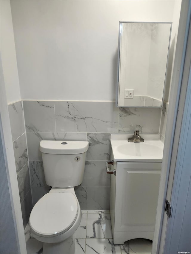 bathroom featuring vanity, toilet, and tile walls