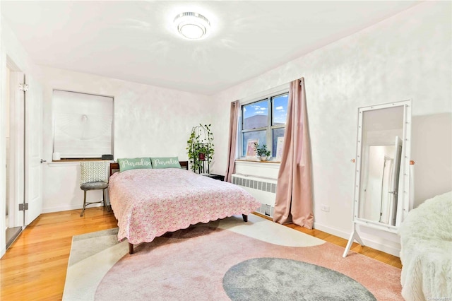 bedroom with radiator and hardwood / wood-style flooring