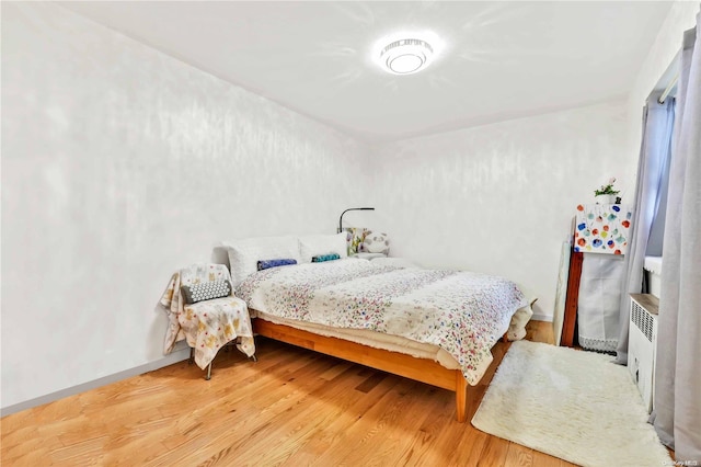 bedroom with wood-type flooring and radiator heating unit