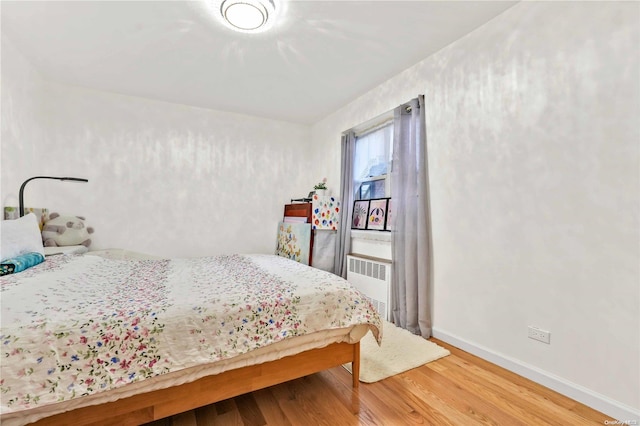 bedroom with radiator and hardwood / wood-style floors