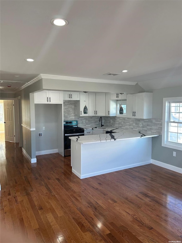 kitchen with kitchen peninsula, dark hardwood / wood-style flooring, stainless steel range, crown molding, and white cabinetry