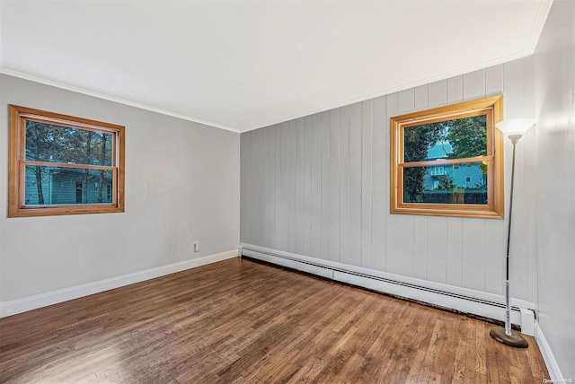 empty room featuring hardwood / wood-style floors, wooden walls, baseboard heating, and ornamental molding