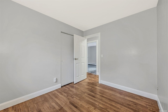 empty room featuring a baseboard radiator and hardwood / wood-style flooring