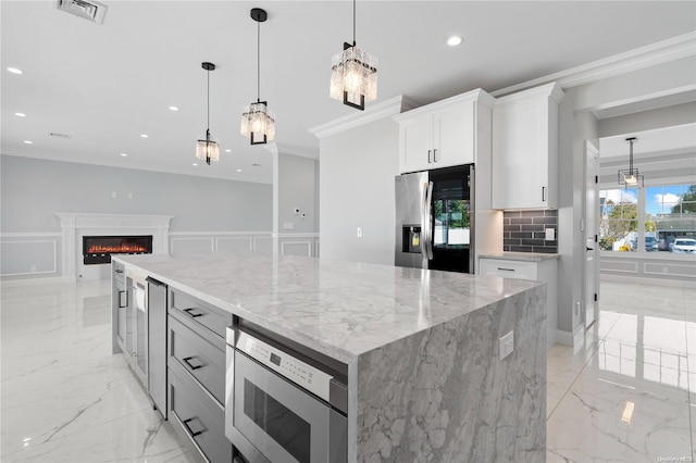 kitchen with hanging light fixtures, a kitchen island, light stone counters, white cabinetry, and stainless steel appliances