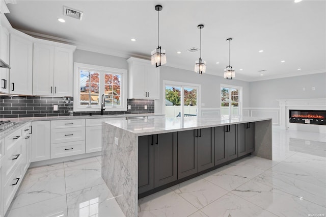 kitchen featuring white cabinets, a wealth of natural light, hanging light fixtures, and a large island