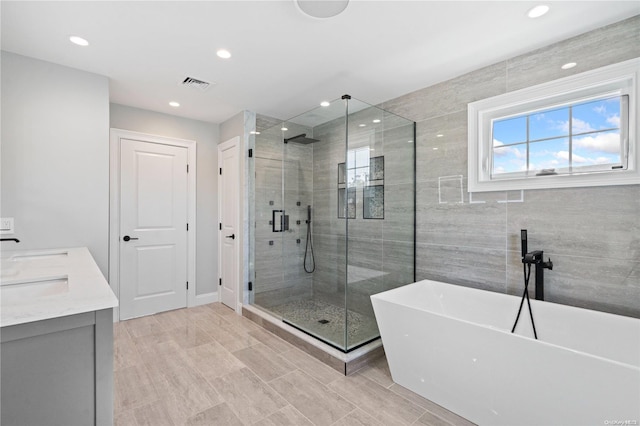 bathroom featuring vanity and independent shower and bath