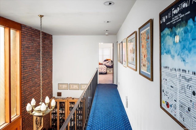 corridor with a chandelier and dark carpet