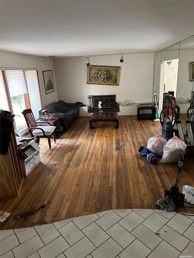 unfurnished living room with brick wall, hardwood / wood-style flooring, and a fireplace