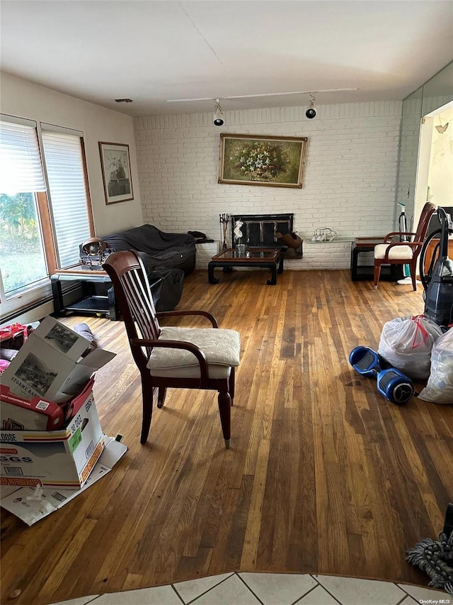 living room featuring brick wall and wood-type flooring