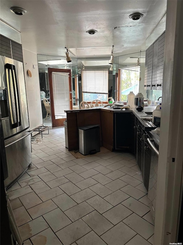 kitchen featuring sink, kitchen peninsula, and stainless steel fridge