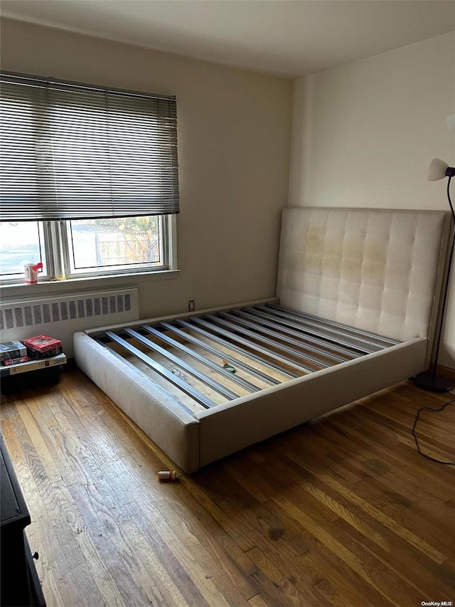 unfurnished bedroom featuring hardwood / wood-style floors and radiator