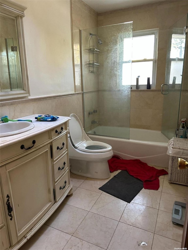 full bathroom featuring toilet, enclosed tub / shower combo, tile patterned floors, vanity, and tile walls